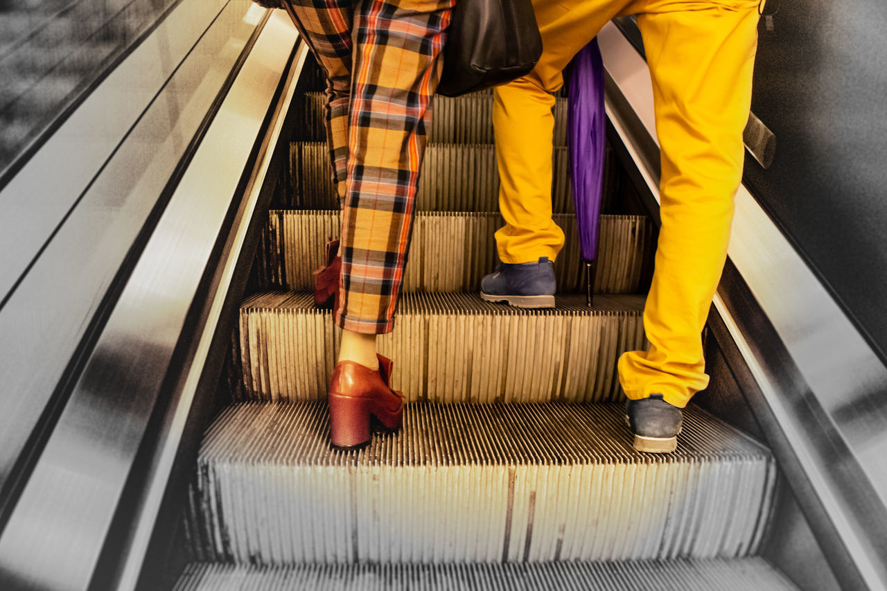LOW SECTION OF MEN STANDING ON ESCALATOR