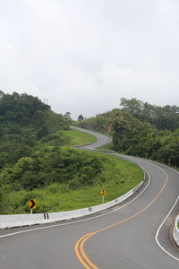 Road by trees against sky