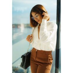 Woman looking at camera while standing by window