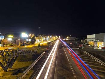 Light trails on road in city against sky at night