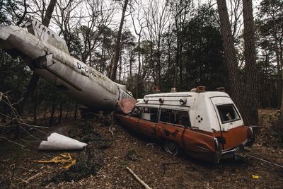 Abandoned airplane crashed with vehicle on field in forest