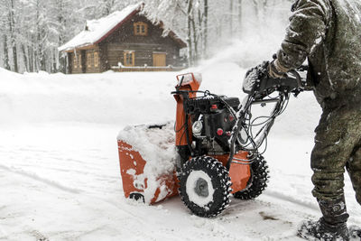 Low section of man using snowblower machine