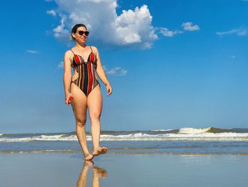 Full length of woman standing at beach against sky