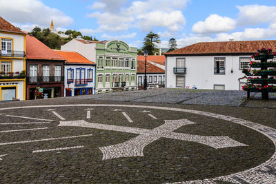 Road by buildings in town against sky