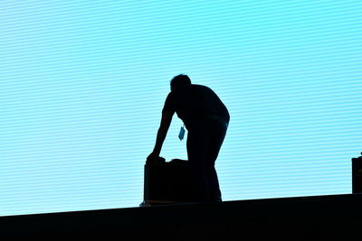 Rear view of silhouette people standing against blue sky