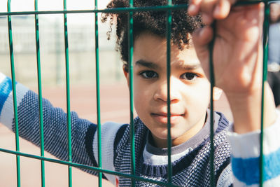 Portrait of cute boy seen through fence