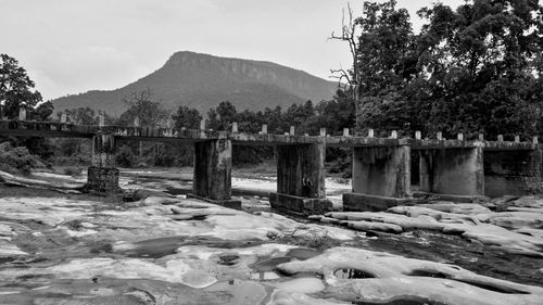 Bridge over river by trees against sky