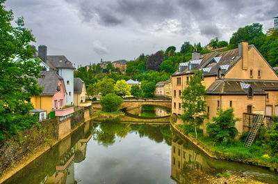 Houses by lake and buildings against sky