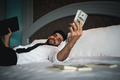 Midsection of man using mobile phone while lying on bed