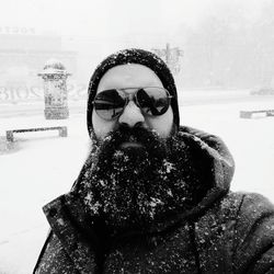 Portrait of man wearing sunglasses during snowfall in city