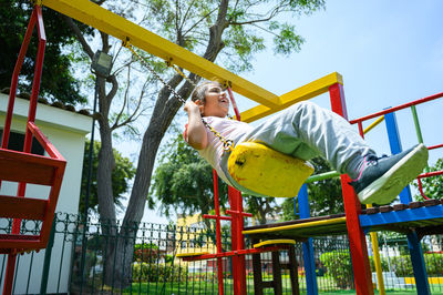 Low angle view of boy swinging at playground