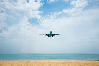 Airplane flying over sea against sky