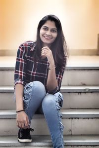 Portrait of smiling young woman sitting on steps