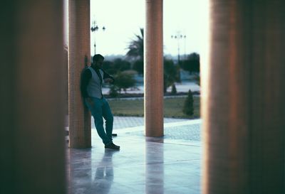 Full length of man checking time while leaning on column