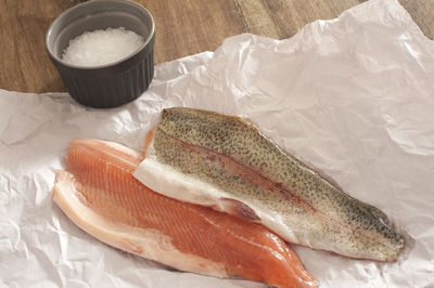 High angle view of salmon with salt on paper at table