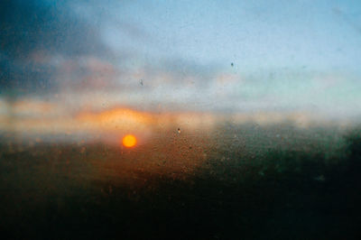 Raindrops on glass window during sunset