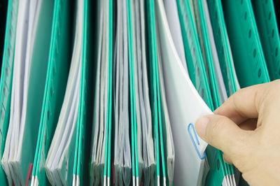 Cropped hand of person holding paper in file