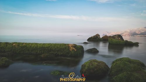 Scenic view of rocks on sea against sky