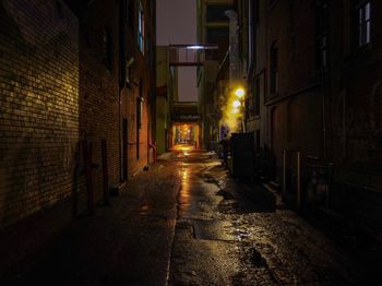 Alley amidst illuminated buildings at night