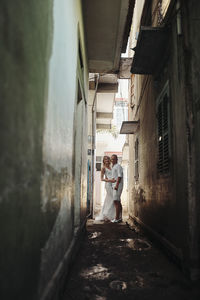 Rear view of woman walking on alley amidst buildings