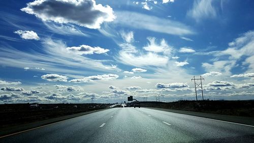 Road amidst field against cloudy sky at dusk