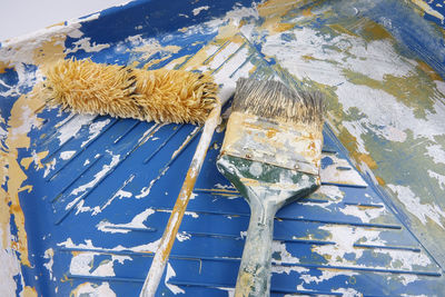 High angle view of paintbrushes and paint roller on tray 