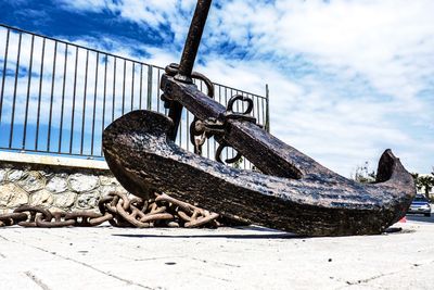 Anchor by street against cloudy sky