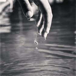 Cropped image of wet hand over lake