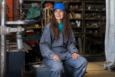 Smiling manual worker sitting on seat in workshop