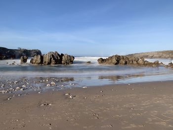 Scenic view of rocks on beach against sky