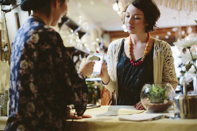 Owner scanning qr code from mobile phone holding by customer in plant shop