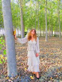 Woman standing by tree in forest during autumn
