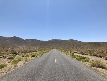 Road amidst landscape against clear blue sky