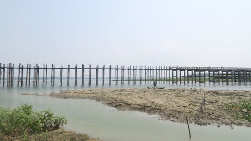 Wooden posts in sea against sky