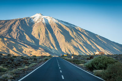 Road amidst mountains against clear sky