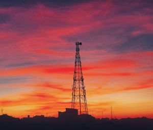 Low angle view of silhouette communications tower against sky during sunset