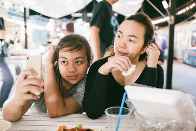 Woman taking selfie with friend in restaurant
