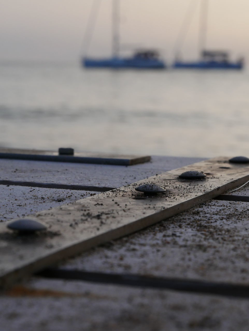 CLOSE-UP OF METAL RAILING BY SEA