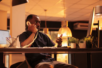 Businessman talking on landline phone at office