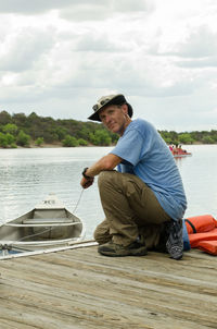 Portrait of man wearing hat on pier against lake