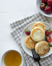 Cottage cheese pancakes, ricotta fritters on ceramic plate with fresh strawberry. 
