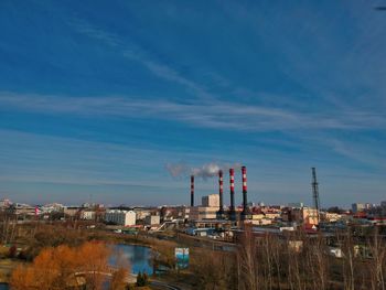 Smoke emitting from factory against sky