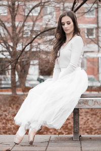 Side view of young woman sitting on bench