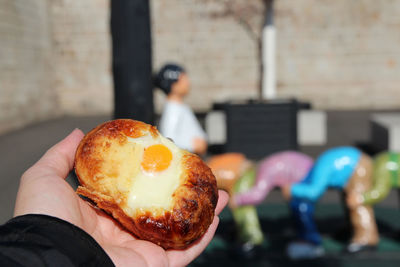 Hand holding the korean egg bread or gyeran-bbang with the blurred street view