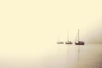 Boats on lake during foggy weather