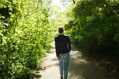 Rear view of woman walking on footpath in forest