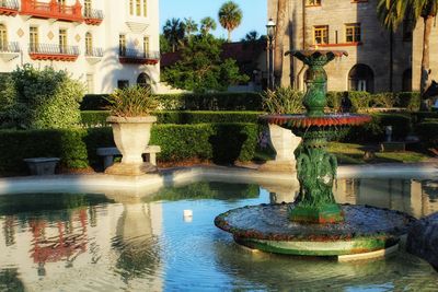 Fountain in pond against building in city