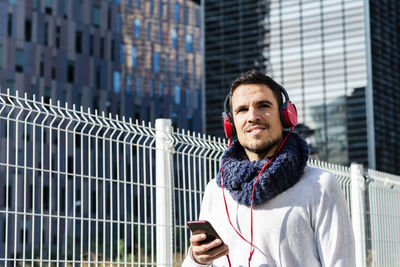 Low angel view of man wearing headphones standing against building