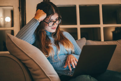 Portrait of young woman sitting on sofa at home