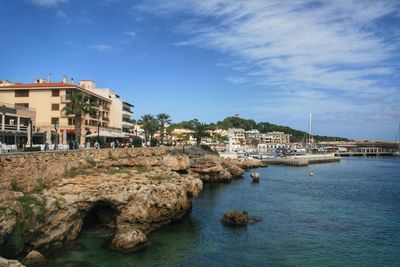 Buildings by sea against sky